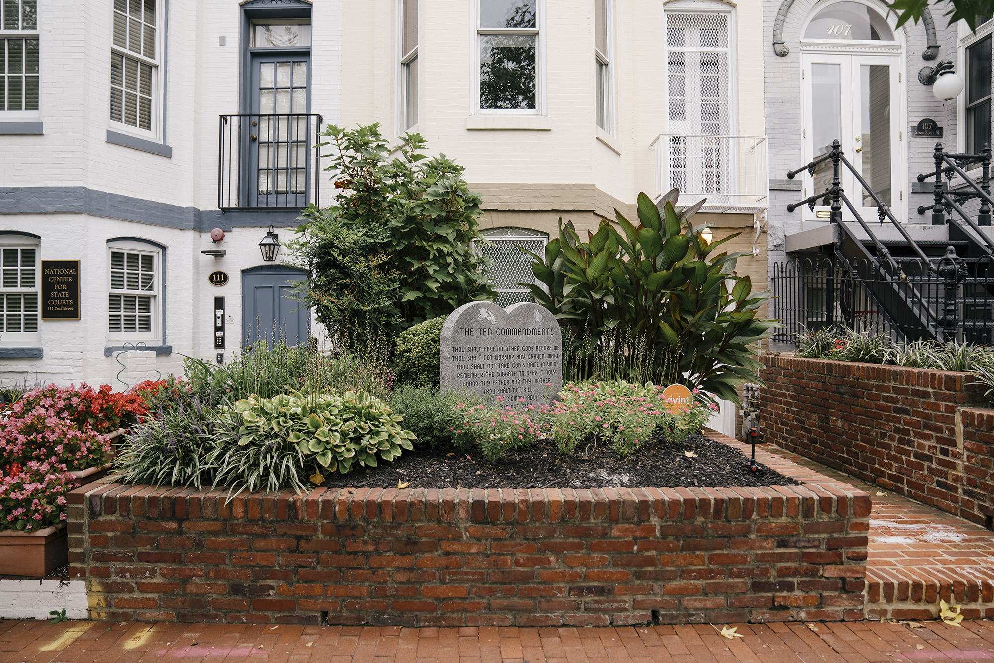 A small statue of the Ten Commandments in front of a row house.