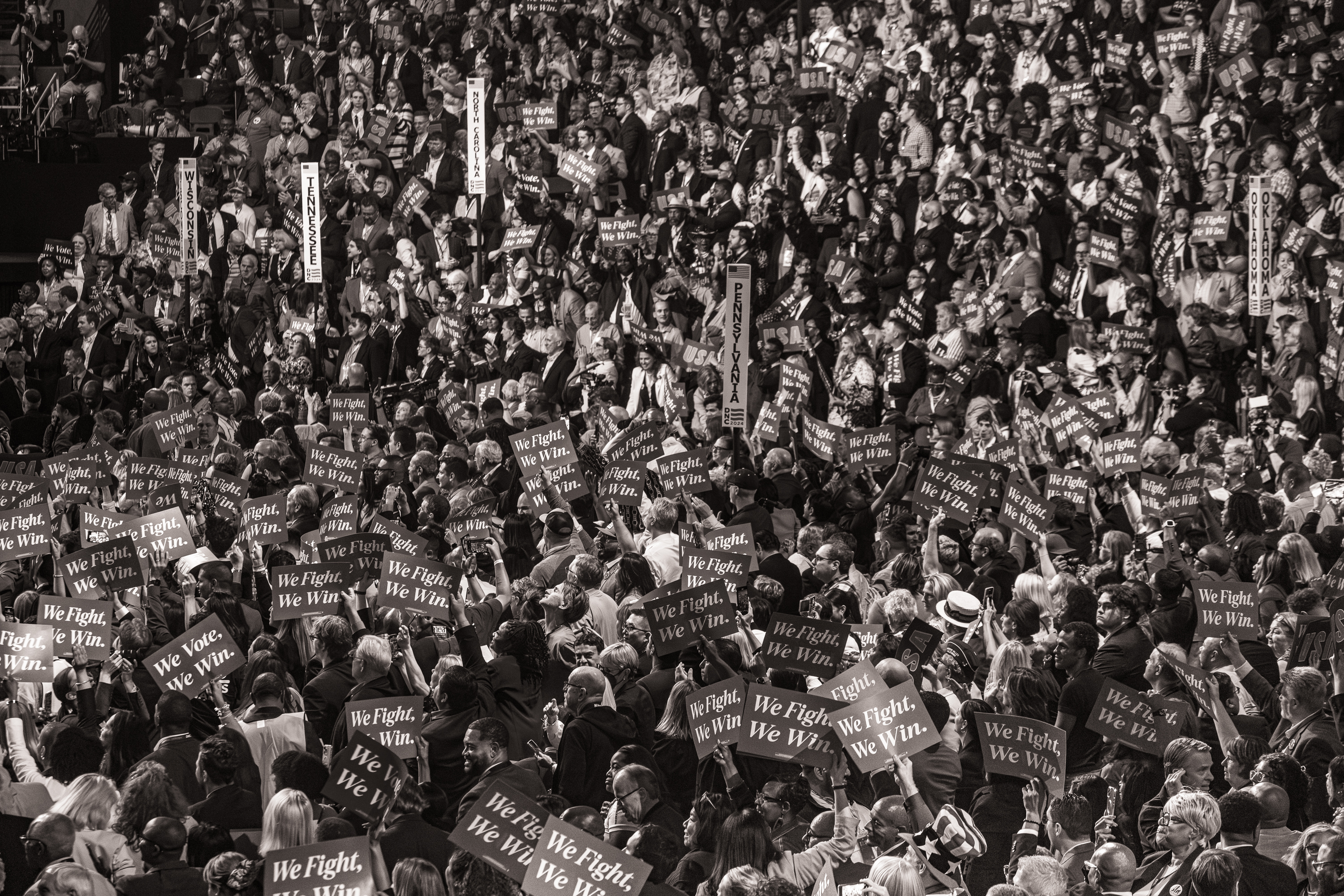 Black and white photo of a large crowd of people with "We Fight We Win" signs.