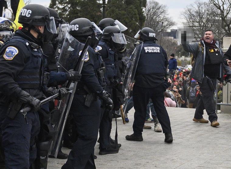 Russell Taylor, right, makes an obscene gesture, obscured by NBC News, at the Capitol on Jan. 6, 2021.