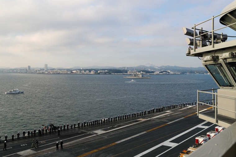 Sailors man the rails on the flight deck as the aircraft carrier