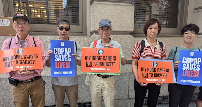 Five protesters stand on a NYC street with signs that read "My home care is not a racket" and "CDPAP Saves Lives"
