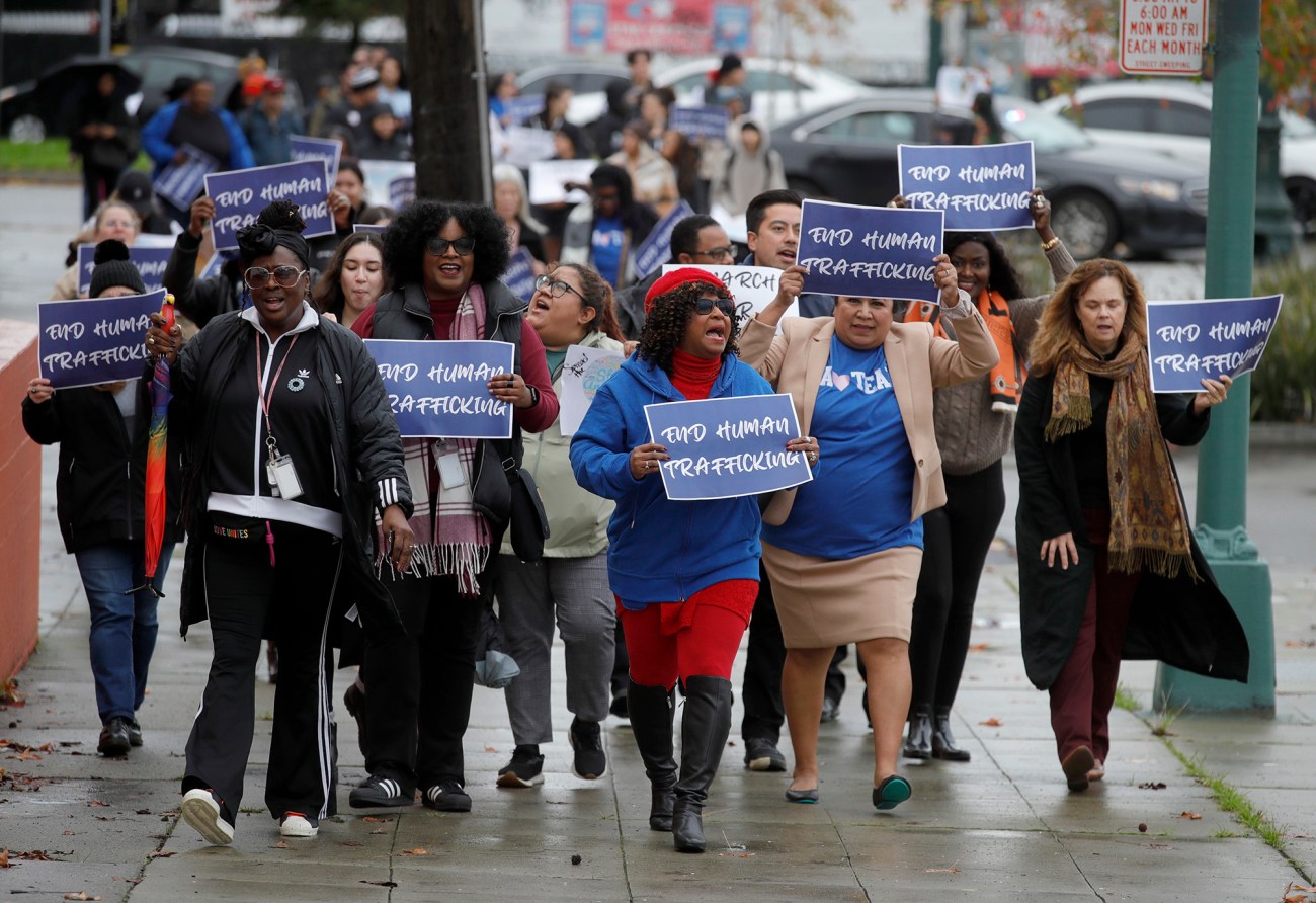 Group of woman walking down a rainy street holding signs that read "End Human Trafficking."