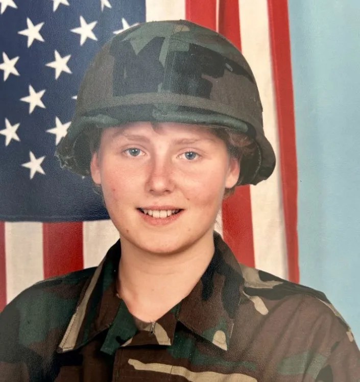 Headshot of Army military police officer Mona McGuire in uniform in front of a US flag.