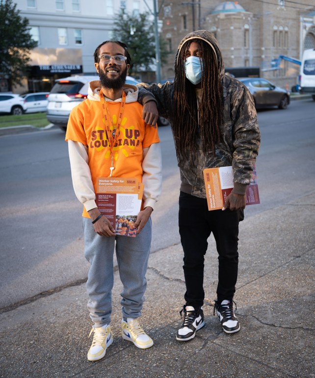 Portrait of two men holding flyers.