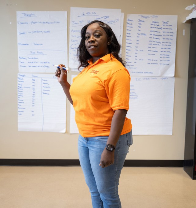 Portrait of a woman holding a marker, wearing a yellow shirt.