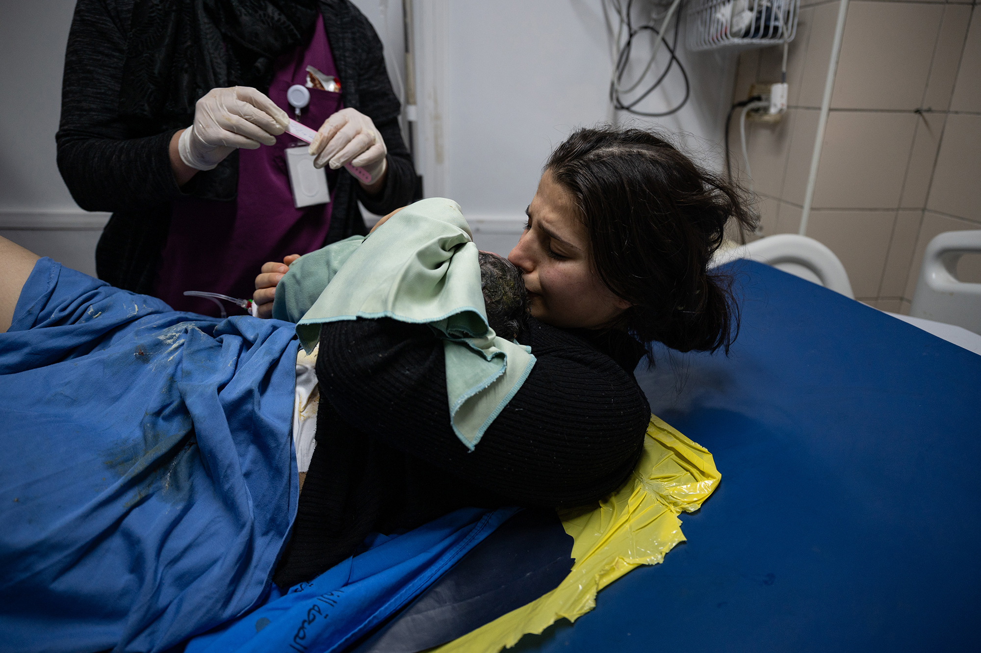 Woman laying in a hospital bed, kissing a baby's head right after giving birth.