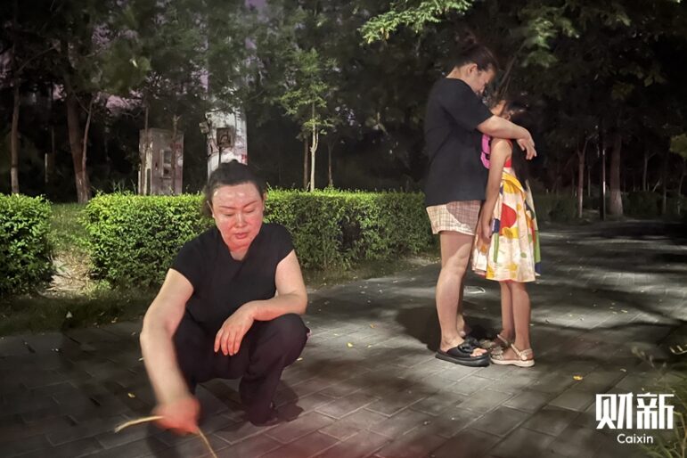 Image: Sun Renze's mother, Ren Tingting, along with her daughter-in-law and granddaughter, burned joss paper on the street to console her son's spirit. Caixin, Wang Heyan