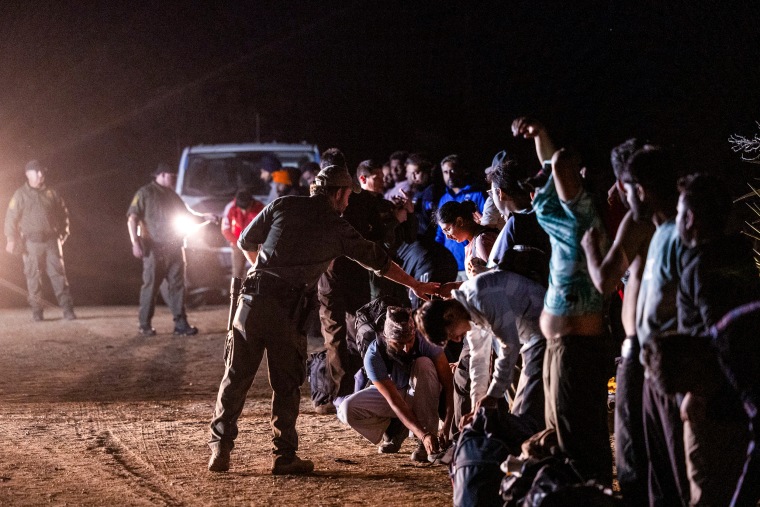 Migrants queue up to be processed by U.S. Border Patrol agents.