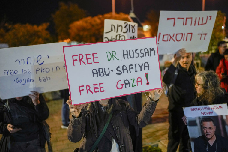 A woman holds a sign that reads "Free Dr. Hussam Abu Safiya, Free Gaza" 