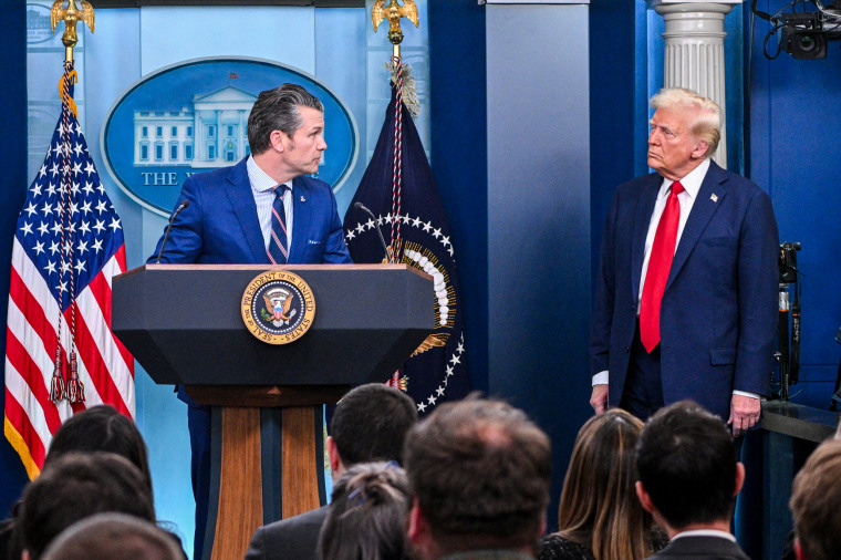 Donald Trump looks on as Pete Hegseth speaks.