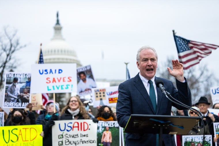 Chris Van Hollen speaks at a podium outside in front of protestors at the Capitol building