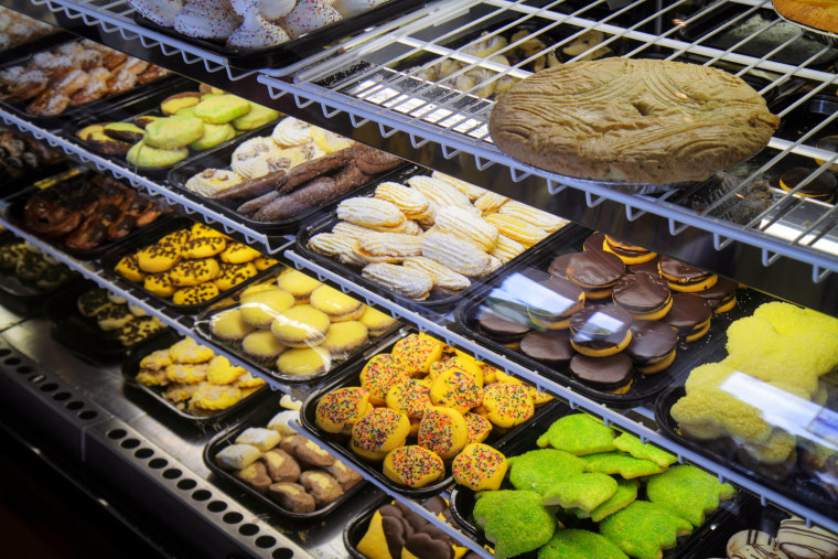 A bakery display case with various colored cookies.