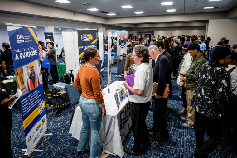 Attendees speak with recruiters inside of an event space